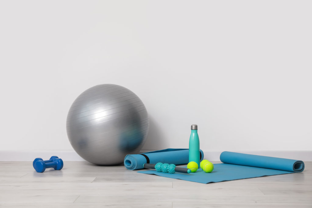 Set,Of,Sports,Equipment,With,Fitness,Ball,Near,Light,Wall